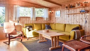 A cozy room with wooden walls, a yellow sofa, a wooden table, and a rocking chair. - Gorgeous home in Sjusjøen with sauna (Sjusjøen)