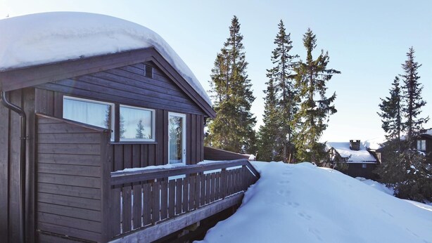 A wooden cabin with a snow-covered roof and a wooden deck. - Gorgeous home in Sjusjøen with sauna (Sjusjøen)