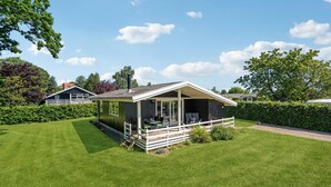 A small, single-story cabin with a porch, surrounded by well-maintained grass and hedges. - 3 bedroom gorgeous home in Hejls (Hejls)