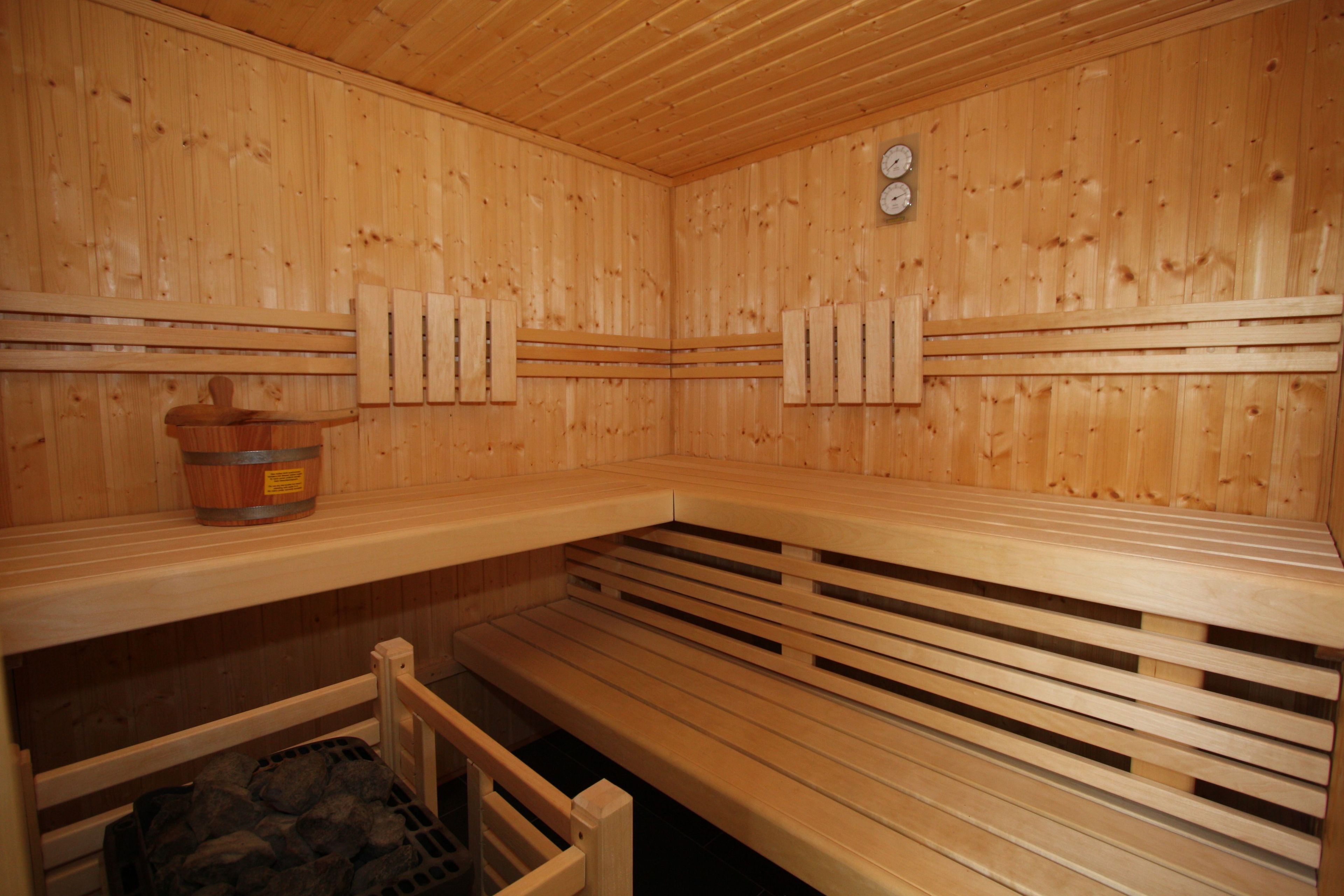 Un sauna avec des bancs en bois, un mur en bois et une horloge.