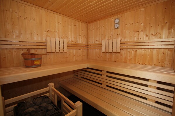 A sauna with wooden benches, a wooden wall, and a clock.