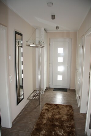 A hallway with a mirror, a glass shelf, a door with light panels, and a brown rug. - Vacation home Residenz am See - Holiday home Residenz am See (50 meters from the (Göhren-Lebbin)