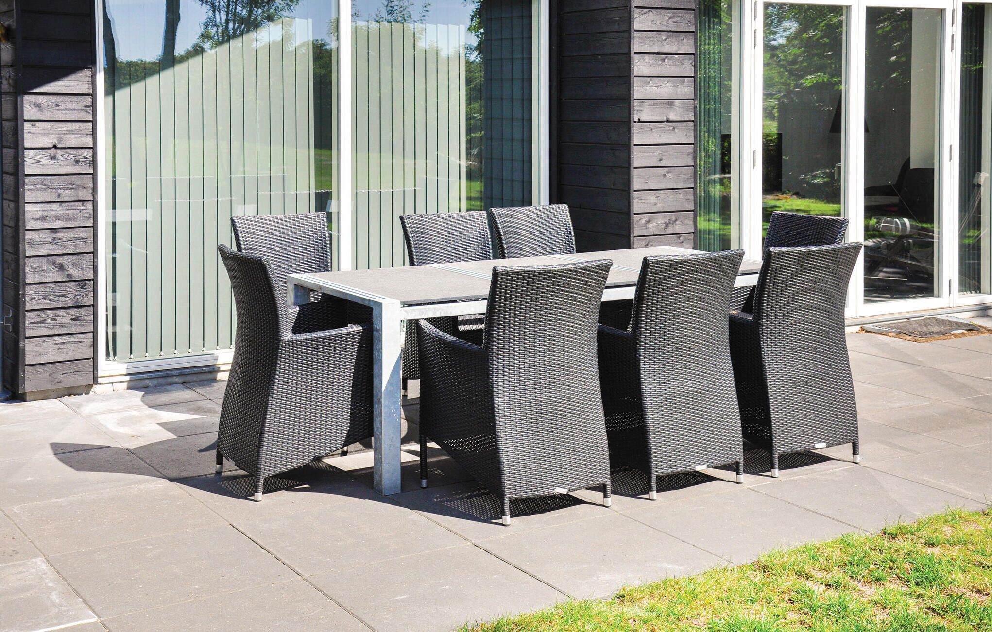 Eine Terrasse mit Tisch und Stühlen, eine Schiebetür und eine Steinmauer.