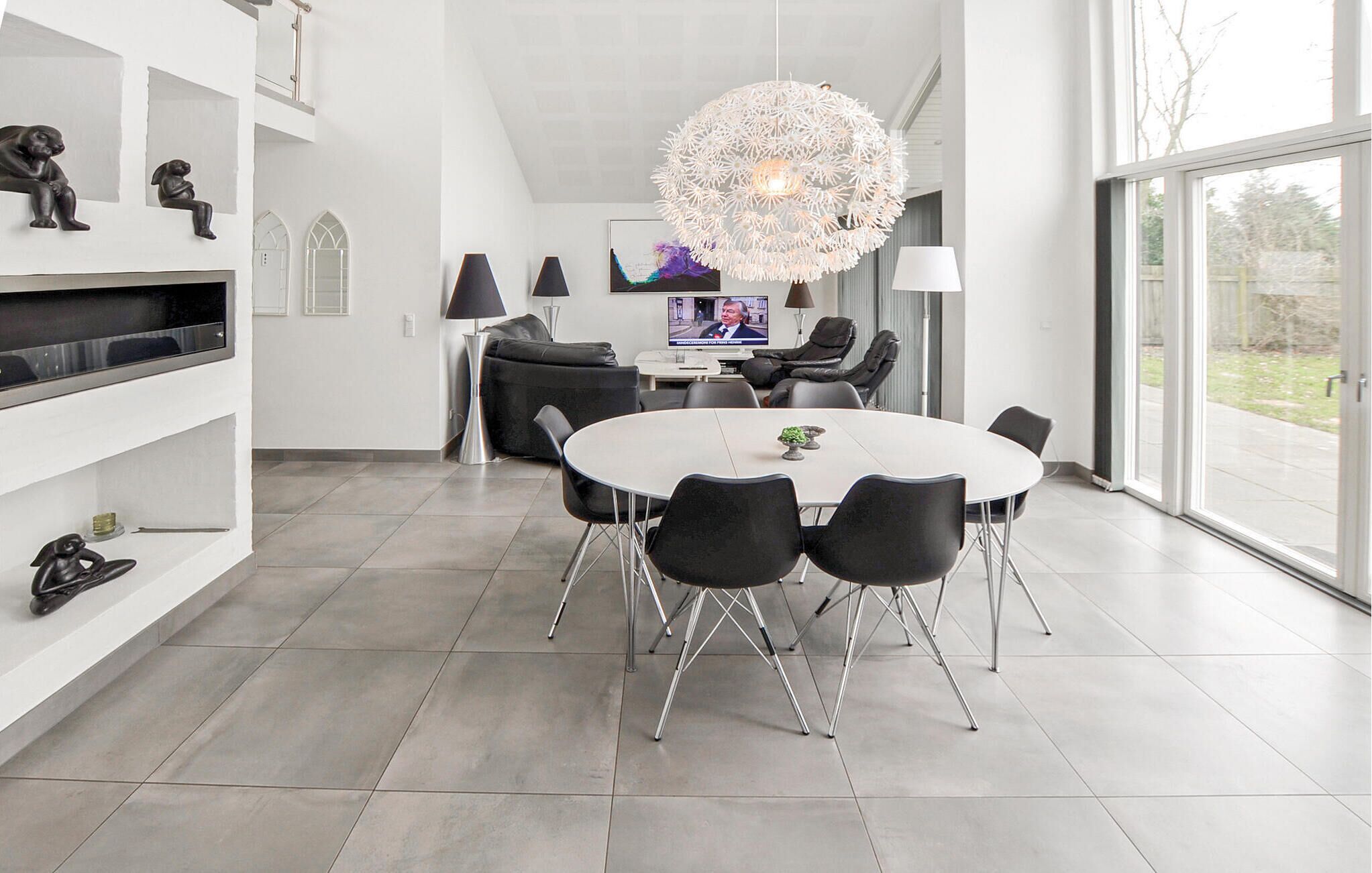 Un espace de salle à manger moderne avec une table ronde, des chaises noires et un lustre original.