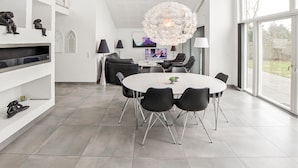 Een moderne eetruimte met een ronde tafel, zwarte stoelen en een bijzondere kroonluchter.