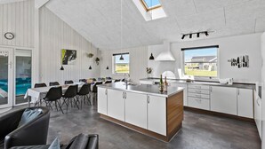 A modern kitchen with a central island, white cabinetry, and a skylight. - Cozy home in Løkken with WiFi (Løkken)