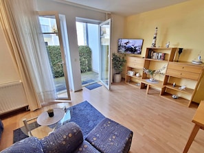 A living room with a sofa, a coffee table, a TV, and a bookshelf.