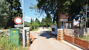 A rural road leading to a gated area with a sign indicating 'Kamp Jurjevac'.