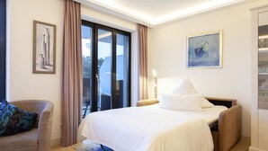 A hotel room with a bed, a chair, a painting, and a sliding glass door. - Lovely apartment in Binz with outdoor swimming pool (Prora/Rügen)