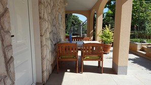 A covered outdoor area with stone walls, wooden chairs, a table, and potted plants. - Ginkgo 1 - One-room apartment near the sea - Apartments Ginkgo, Pula-Banjole (Banjole)