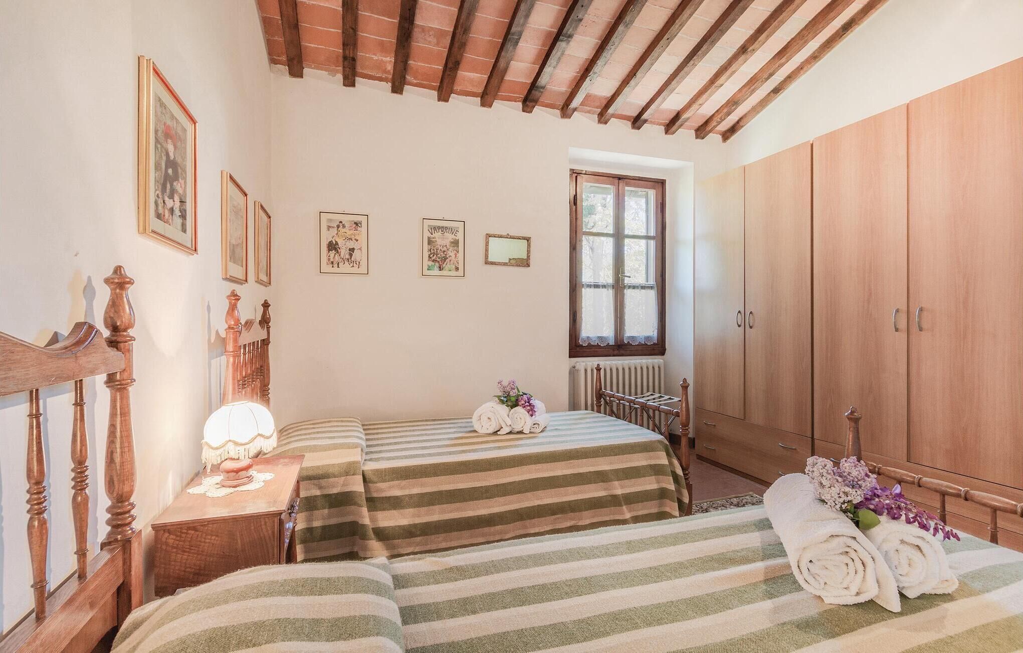 A bedroom with two beds, a wooden wardrobe, a window, and a radiator.