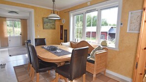 Un comedor con una mesa de madera, sillas negras y un banco. Hay una ventana con vistas al exterior, un reloj en la pared y un mapa en la pared.