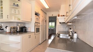 Una cocina moderna con armarios blancos, electrodomésticos de acero inoxidable y una encimera amplia.