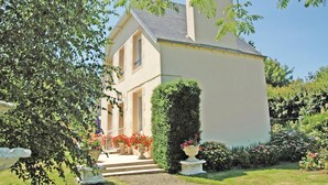 Ein zweigeschossiges Haus mit gepflegtem Garten, einem Kiesweg, der zum Eingang führt, und verschiedenen blühenden Pflanzen.