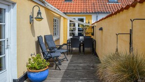 A wooden deck with outdoor furniture, a potted plant, and a view of the building's interior. - 3 bedroom stunning home in Sæby (Sæby)