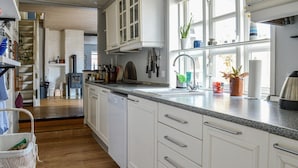 A kitchen with white cabinets, a granite countertop, and a window with plants. - 3 bedroom stunning home in Sæby (Sæby)