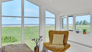 A spacious room with large windows offering a view of a beach and ocean. - Beautiful home in Skjern with sauna (Skjern)