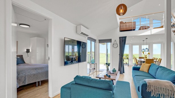 A spacious living area with a large TV, a dining table, and a sofa. - Beautiful home in Skjern with sauna (Skjern)