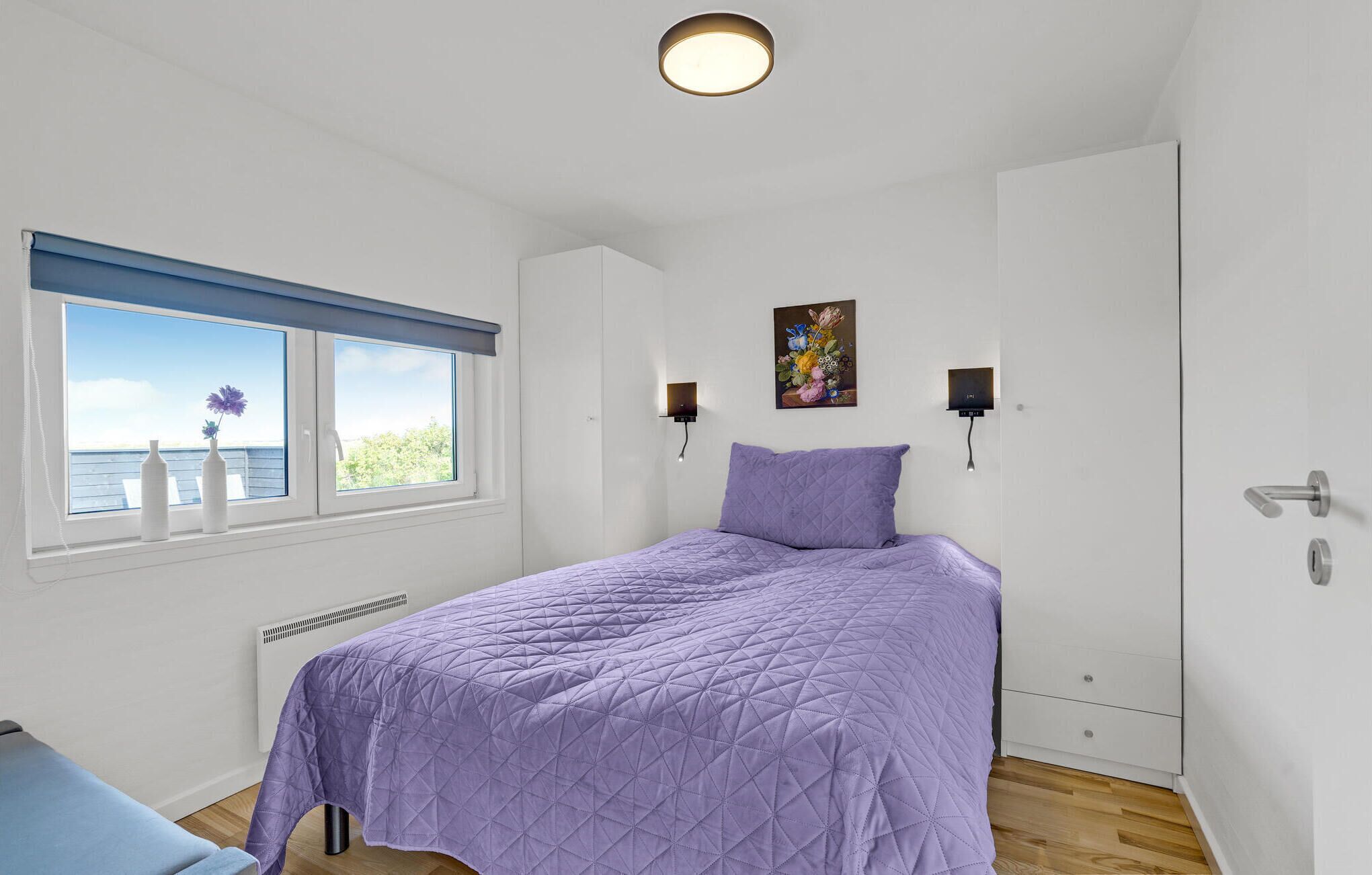 A bedroom with a bed, a window with a view, a radiator, and a door.