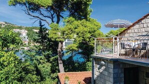 A balcony with a stone wall, a view of a coastal town, and a striped umbrella. - Awesome apartment in Dubrovnik with WiFi (Dubrovnik)