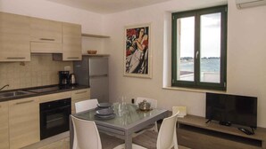 Una cocina moderna con comedor, un cuadro en la pared y vista al mar a través de una ventana.