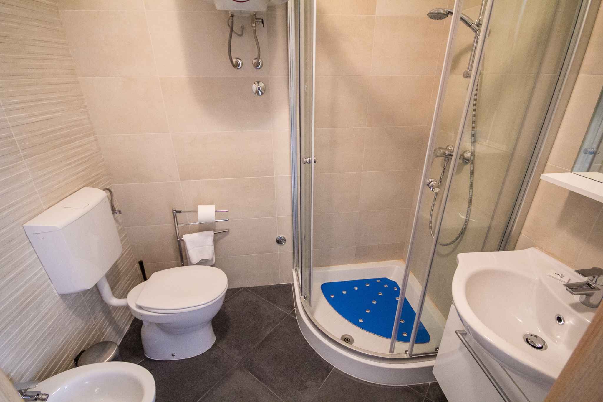 A modern bathroom with a toilet, bidet, and a glass-enclosed shower area.