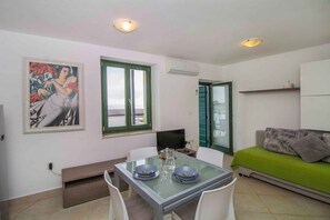 Un espace repas comprenant une table, des chaises, un tableau, un téléviseur et un canapé.