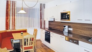 A compact kitchen with white cabinets, a wooden countertop, a built-in microwave, and a coffee maker.