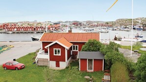 Een kustdorp met rode huizen, een jachthaven met boten, en een rode auto op de voorgrond.