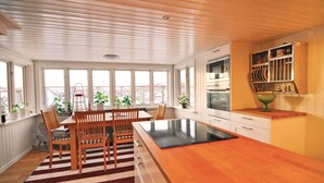 Een keuken met een houten kookeiland, witte kasten en een uitzicht door grote ramen.