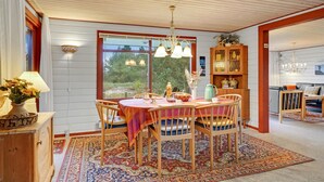 A dining area with a round table, chairs, a chandelier, and a view of greenery outside. - Pet friendly home in Rømø (Rømø)