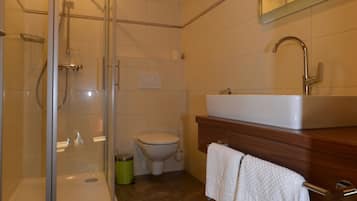 Ein Badezimmer mit Glasdusche, Toilette und Waschbecken mit Holzschrank.