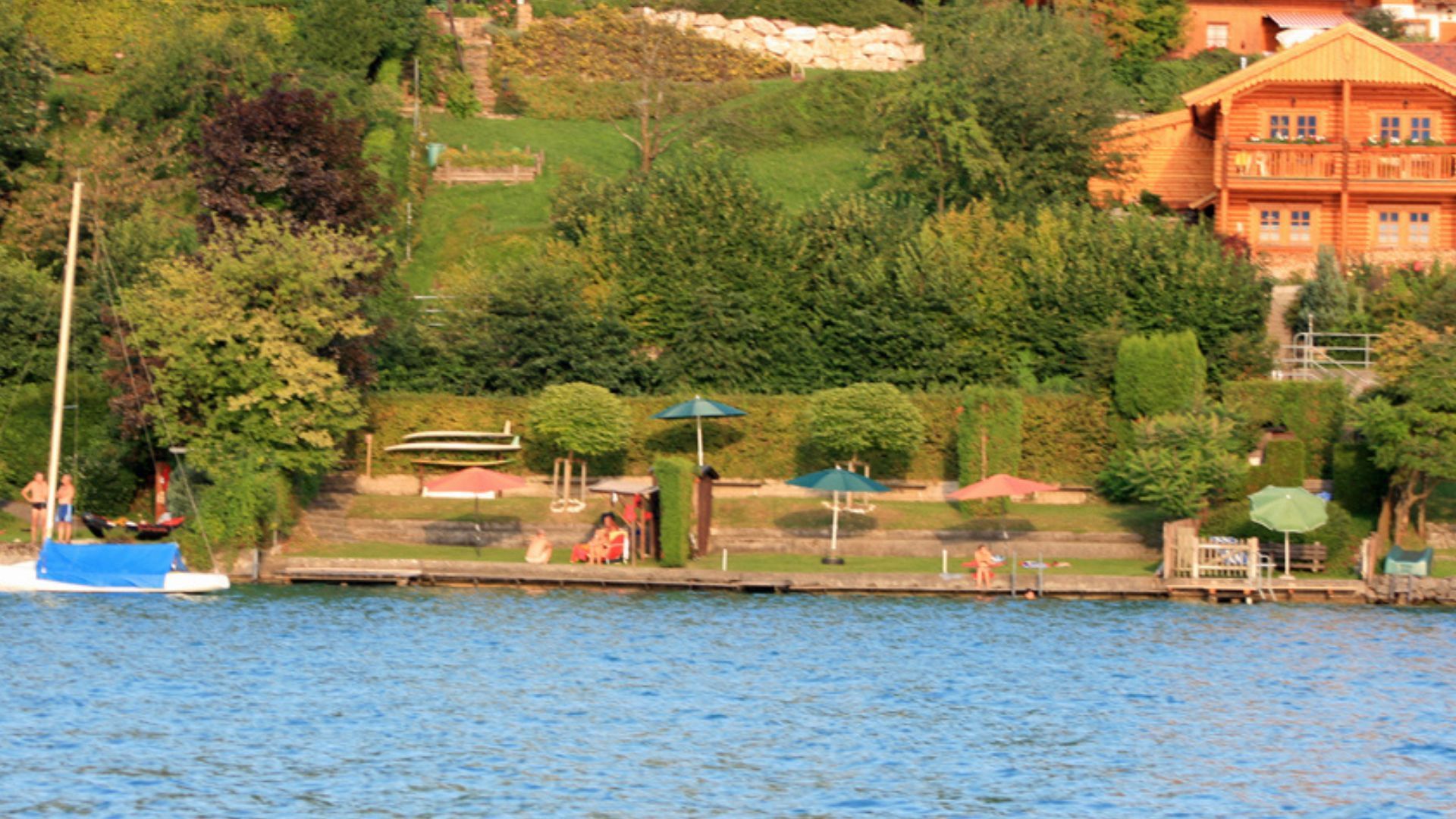 A lakeside view with a wooden house, dock, and boats.