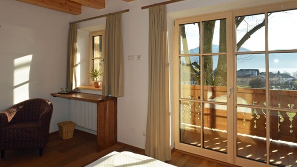 Un dormitorio con un gran ventanal corredero, un banco de madera afuera y una planta en maceta en el alféizar.