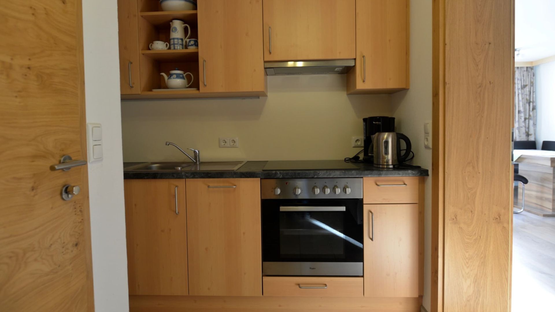 Une cuisine compacte avec des meubles en bois, un four en acier inoxydable, une machine à café et un évier.