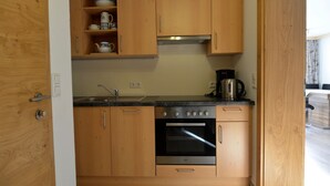 Eine kleine Küche mit Holzausstattung, einem Edelstahlbackofen, einer Kaffeemaschine und einem Spülbecken.