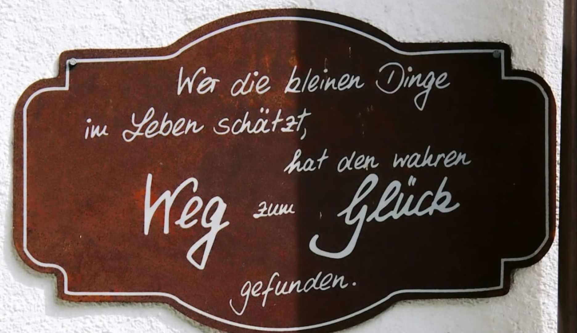 A sign with text in German, mounted on a wall.