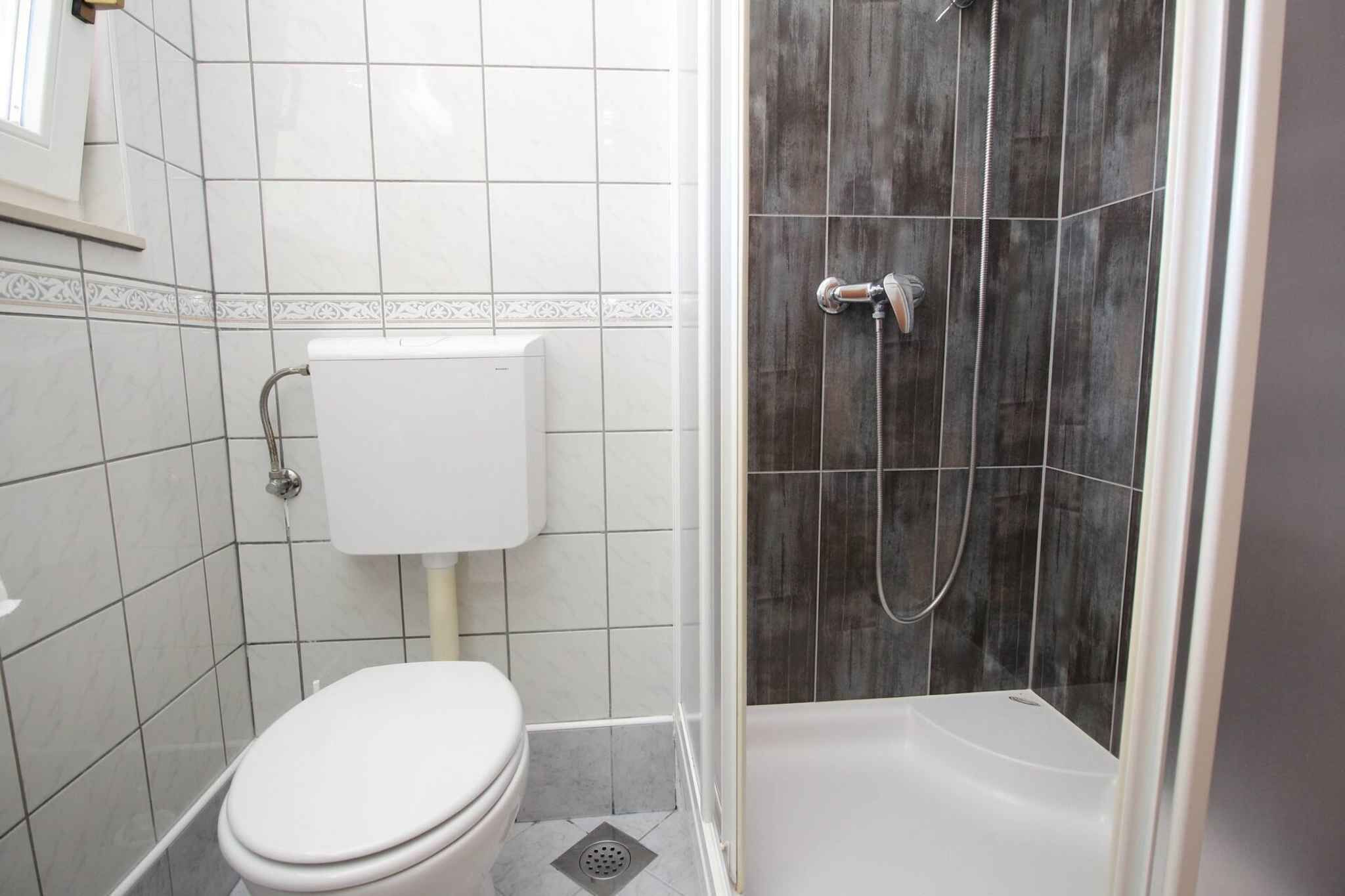 Et badeværelse med toilet, bruser og badekar.