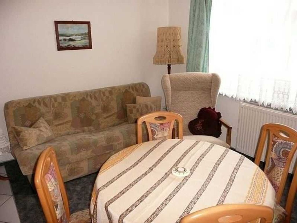 A living room with a sofa, a round table, and two chairs.