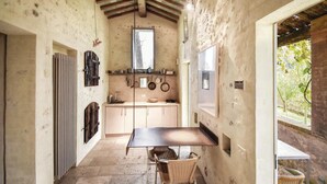 Une cuisine rustique avec une table et des chaises en bois, une fenêtre et une vue sur la verdure à l’extérieur.