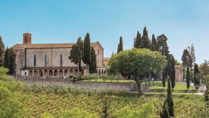 Un bâtiment historique doté d’une cour intérieure, entouré d’arbres et d’un vignoble.