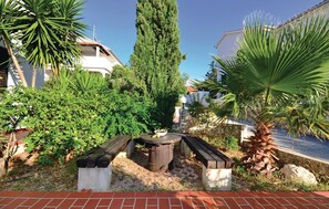 Relax in a serene outdoor seating area surrounded by lush greenery and a rustic wooden table.