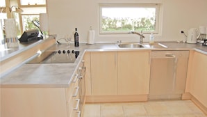 A modern kitchen with a built-in dishwasher, a stainless steel sink, and a window providing natural light. - 4 bedroom gorgeous home in Bogø By (Bogø By)