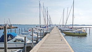 A wooden pier with boats docked on both sides, leading to a calm body of water. - 4 bedroom gorgeous home in Bogø By (Bogø By)