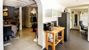 A compact kitchen with a built-in oven, a refrigerator, and a wooden table with kitchen tools. - Awesome home in La Seyne Sur Mer (La Seyne Sur Mer)
