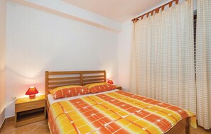 Quarto com cama de madeira, duas luminárias de cabeceira, mesa de cabeceira e janela com cortinas.