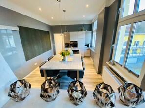 Une cuisine moderne avec des meubles blancs, un îlot central et un coin repas comprenant une table et des chaises.