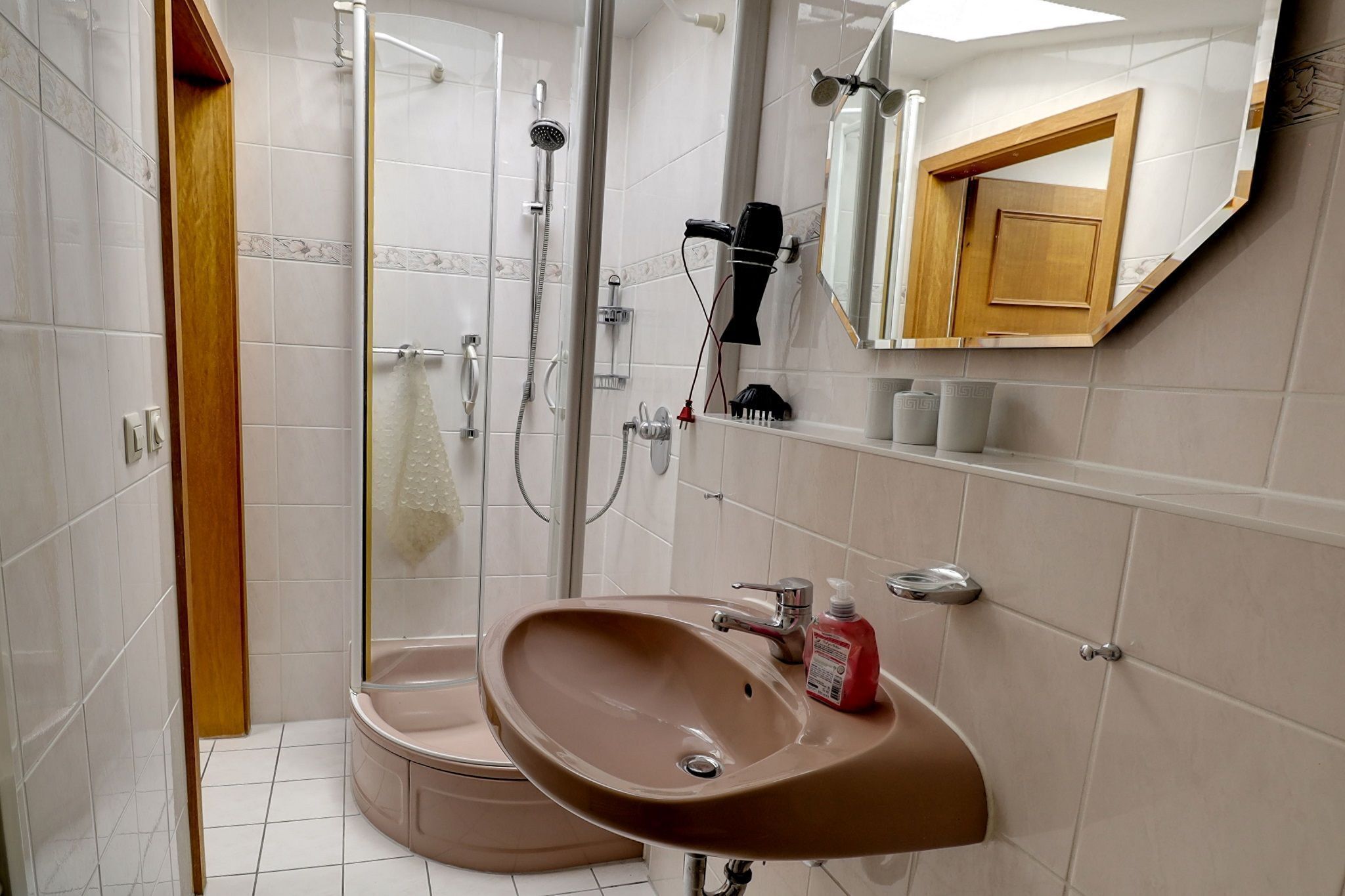 A bathroom with a shower, a sink, a mirror, and a towel rack.