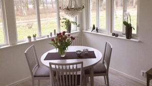 A dining area with a round table, four chairs, a vase of flowers, and a chandelier. - 1 bedroom awesome home in Sölvesborg (Sölvesborg)