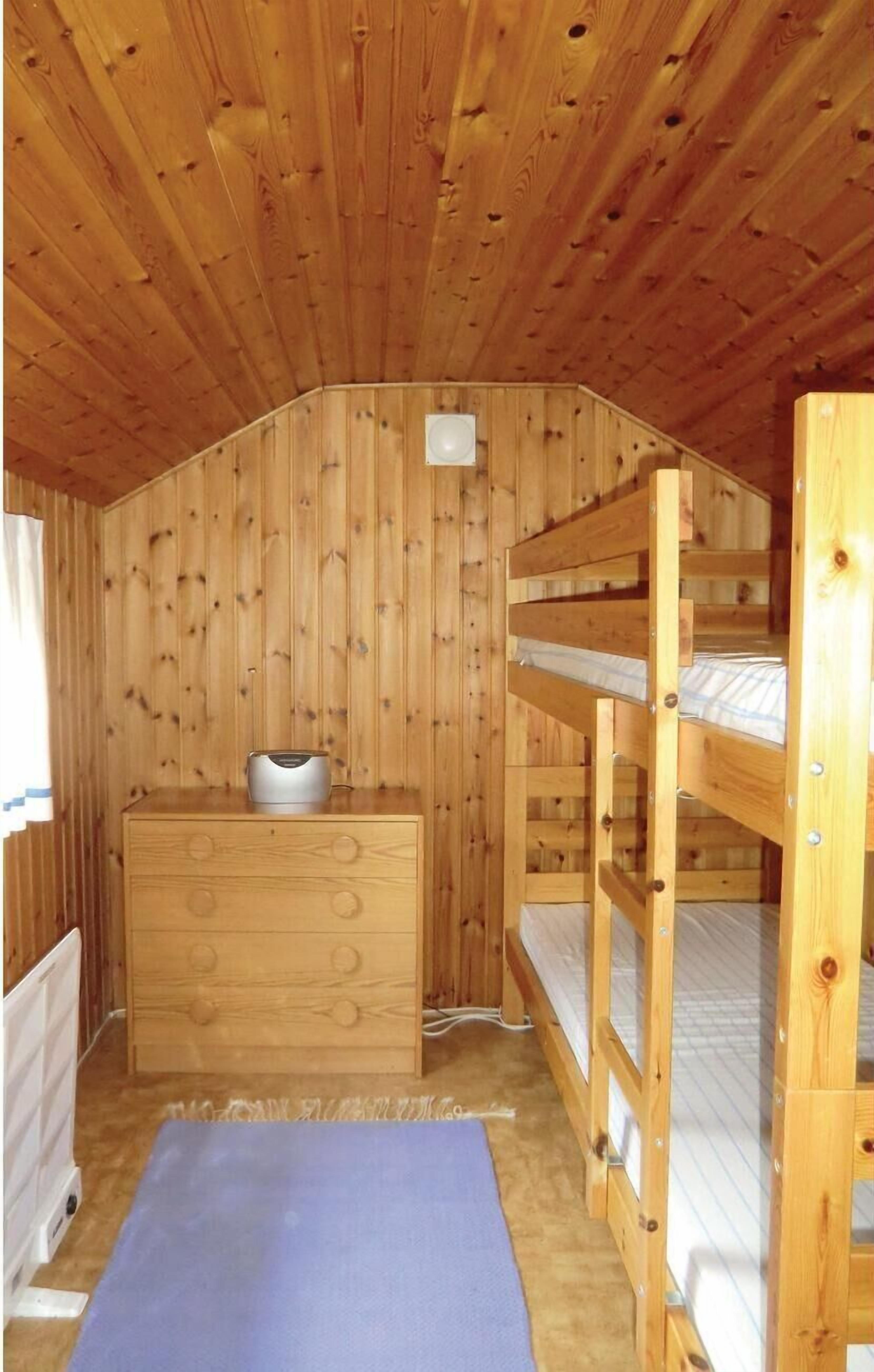 A wooden cabin room with bunk beds, a dresser, and a heater.